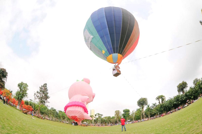 Lễ hội rực rỡ sắc màu với đủ loại khinh khí cầu, đáng chú ý là chú heo hồng dễ thương bay lơ lửng phía xa.