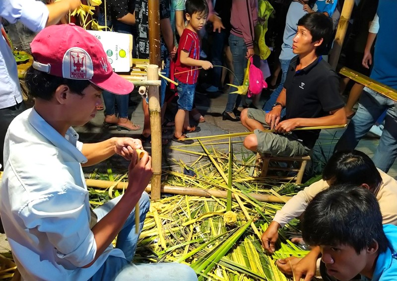 Nghệ nhân khéo léo tạo nên những món đồ độc đáo từ lá dừa, thu hút du khách tại phố đi bộ. (Ảnh: Nguyễn Nhân)