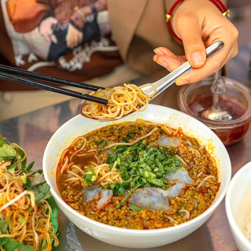 Bún riêu cay nồng, rau thơm, đậu phộng, xoài bào, bánh tráng nướng, nước dùng - món ngon vỗ về dạ dày đói.