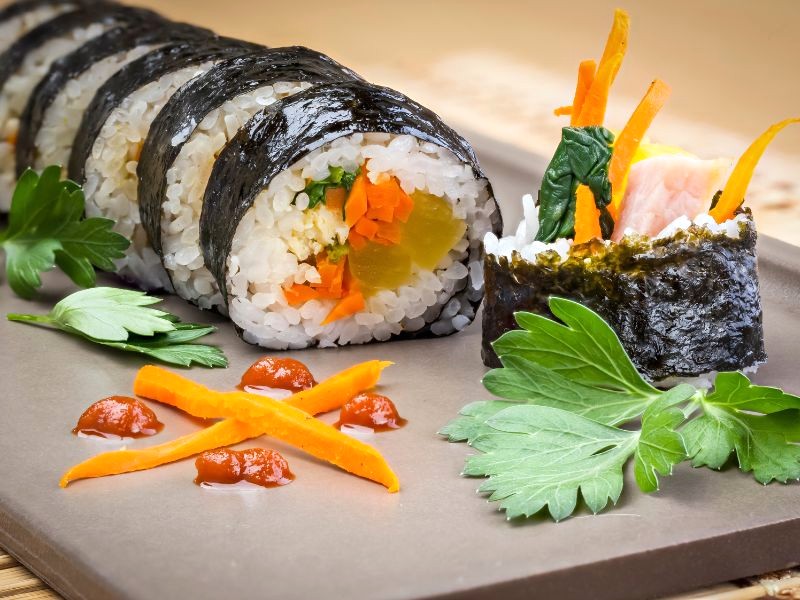 Kimbap là món ăn truyền thống Hàn Quốc, kết hợp rong biển, cơm, trứng và các loại rau củ, tạo nên hương vị độc đáo. (148 ký tự)