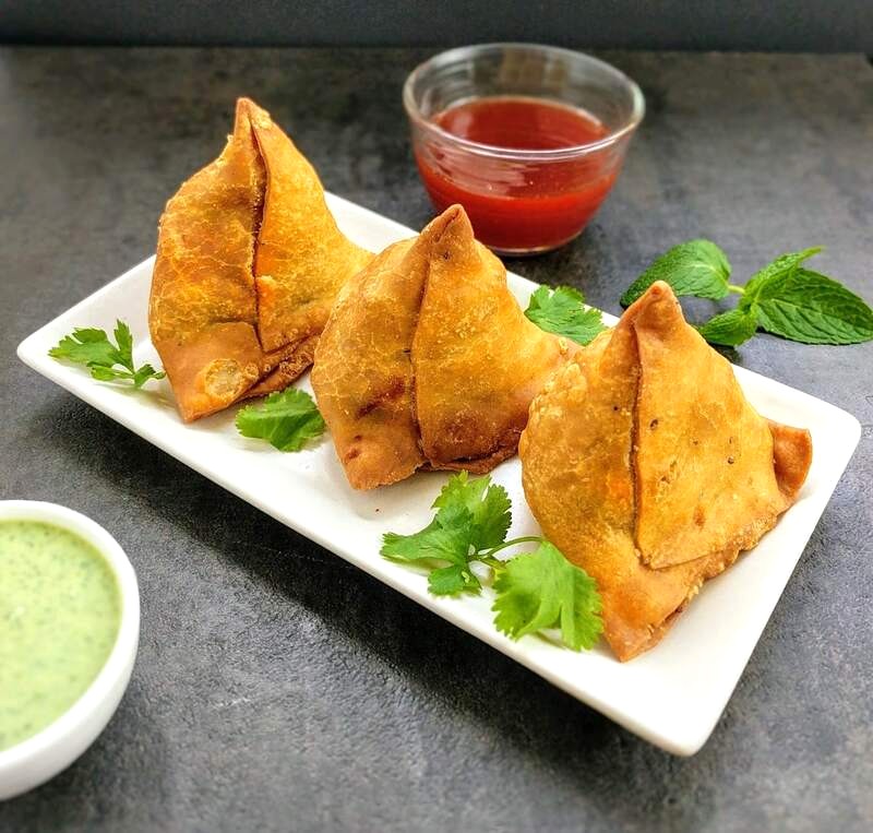 Samosa giòn tan, chấm sốt chua cay, rắc thêm ngò.