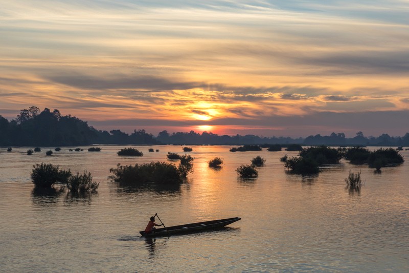 Ngư dân chèo thuyền pirogue trên dòng nước bình minh, Don Det, Si Phan Don. (Ảnh: Basile Morin)